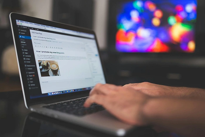 Person typing on a laptop, doing content creation with a website editor in a digital marketing agency.